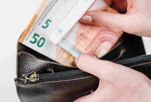 Frau steckt drei Geldscheine in Geldbörse